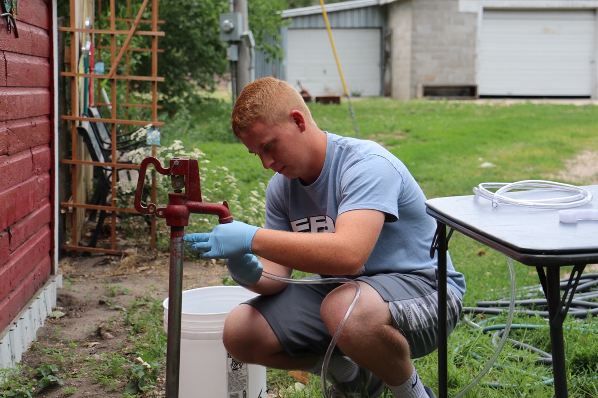 Person sampling water from Well